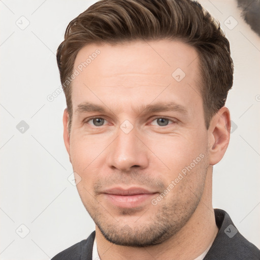 Joyful white young-adult male with short  brown hair and grey eyes