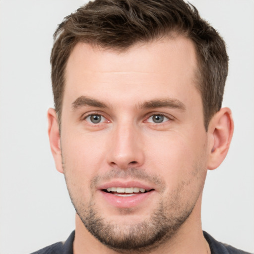 Joyful white young-adult male with short  brown hair and grey eyes