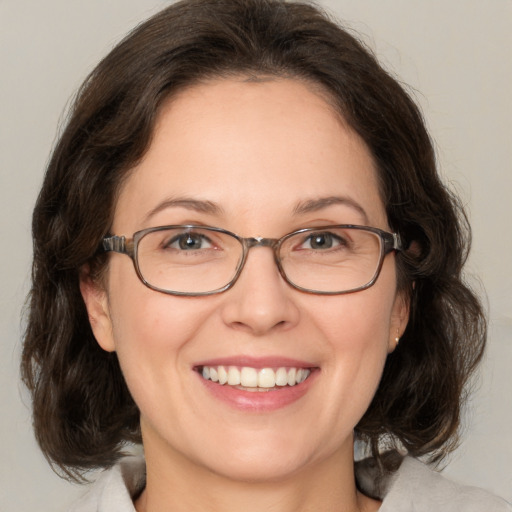 Joyful white adult female with medium  brown hair and green eyes