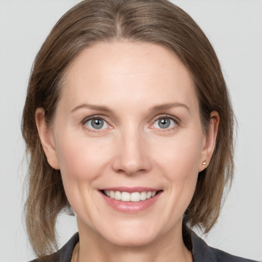 Joyful white young-adult female with medium  brown hair and grey eyes