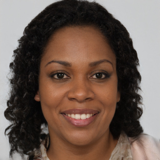 Joyful black young-adult female with long  brown hair and brown eyes
