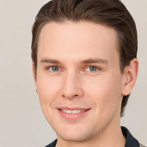 Joyful white young-adult male with short  brown hair and grey eyes