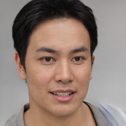 Joyful asian young-adult male with short  brown hair and brown eyes