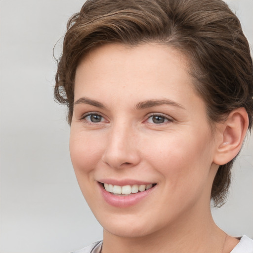 Joyful white young-adult female with short  brown hair and grey eyes