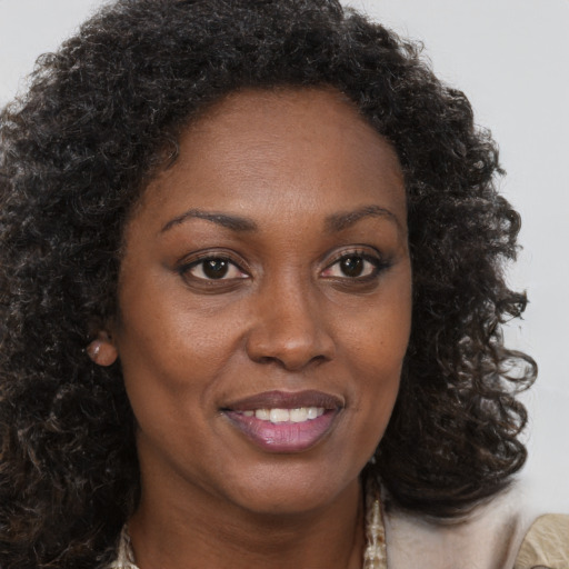 Joyful black young-adult female with long  brown hair and brown eyes