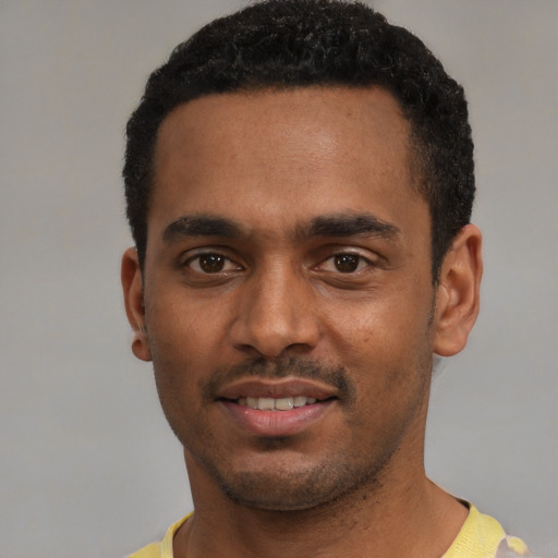 Joyful black young-adult male with short  black hair and brown eyes