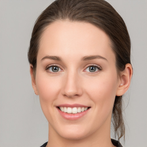 Joyful white young-adult female with medium  brown hair and grey eyes