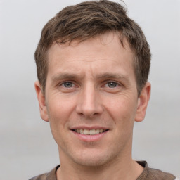 Joyful white young-adult male with short  brown hair and grey eyes