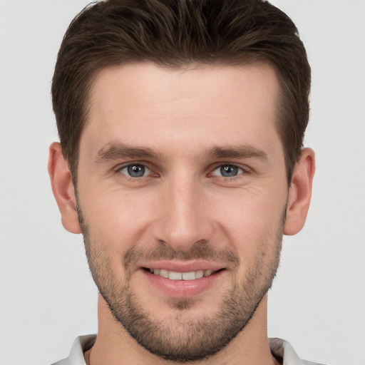 Joyful white young-adult male with short  brown hair and grey eyes