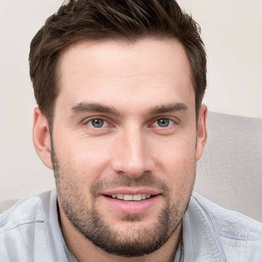 Joyful white young-adult male with short  brown hair and grey eyes