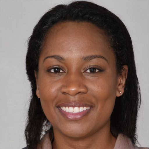 Joyful black young-adult female with long  brown hair and brown eyes