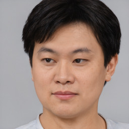 Joyful asian young-adult male with short  brown hair and brown eyes
