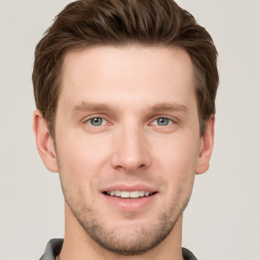 Joyful white young-adult male with short  brown hair and grey eyes