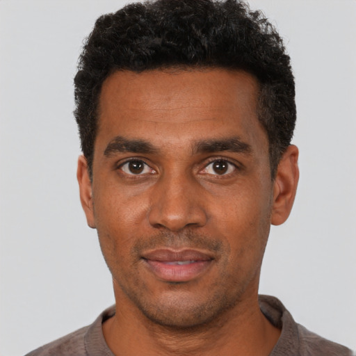 Joyful black young-adult male with short  black hair and brown eyes