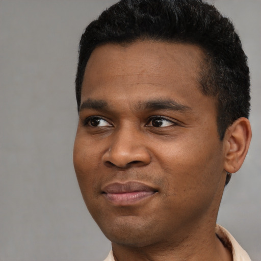 Joyful black young-adult male with short  black hair and brown eyes
