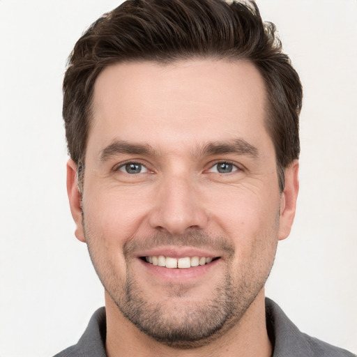 Joyful white young-adult male with short  brown hair and grey eyes