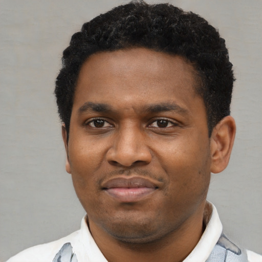 Joyful black young-adult male with short  black hair and brown eyes