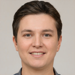 Joyful white young-adult male with short  brown hair and grey eyes