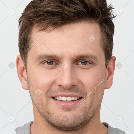 Joyful white young-adult male with short  brown hair and grey eyes