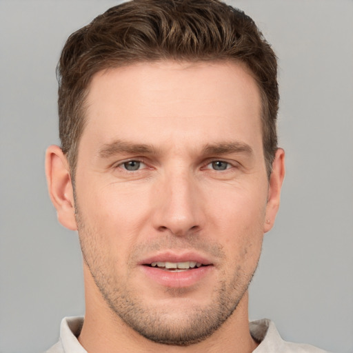 Joyful white young-adult male with short  brown hair and grey eyes