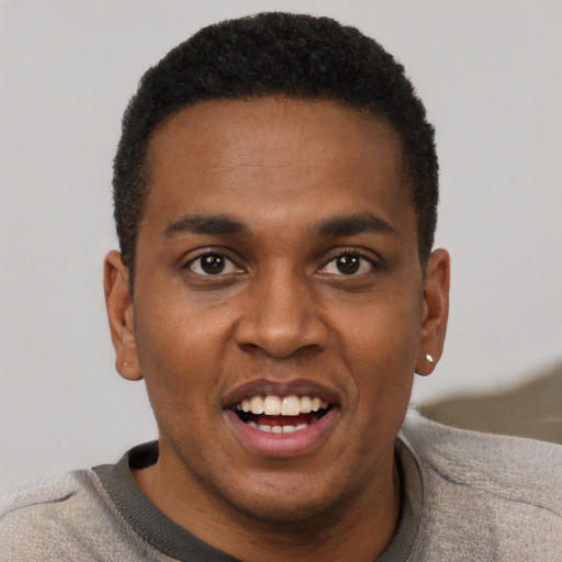 Joyful black young-adult male with short  black hair and brown eyes