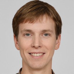 Joyful white young-adult male with short  brown hair and grey eyes