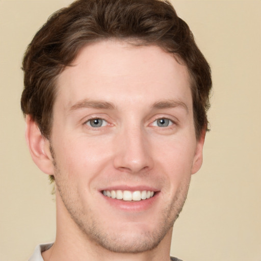 Joyful white young-adult male with short  brown hair and grey eyes