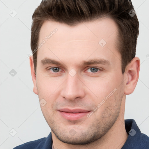 Joyful white young-adult male with short  brown hair and grey eyes