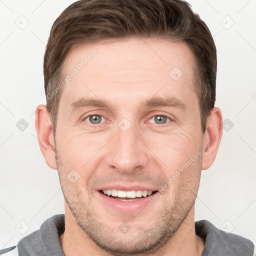 Joyful white young-adult male with short  brown hair and grey eyes