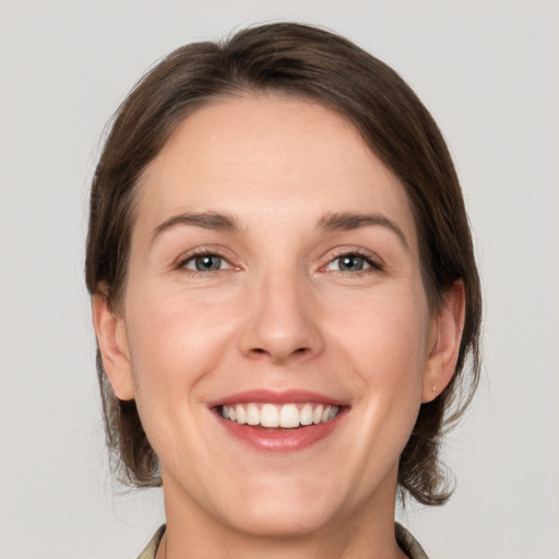 Joyful white young-adult female with medium  brown hair and grey eyes