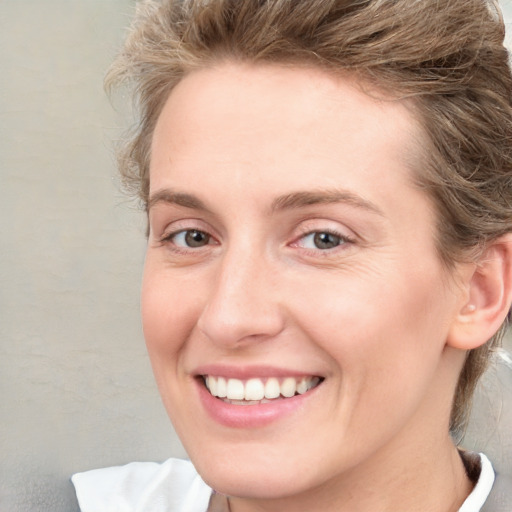 Joyful white young-adult female with short  brown hair and blue eyes