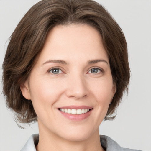 Joyful white young-adult female with medium  brown hair and grey eyes