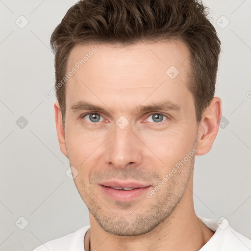 Joyful white young-adult male with short  brown hair and grey eyes