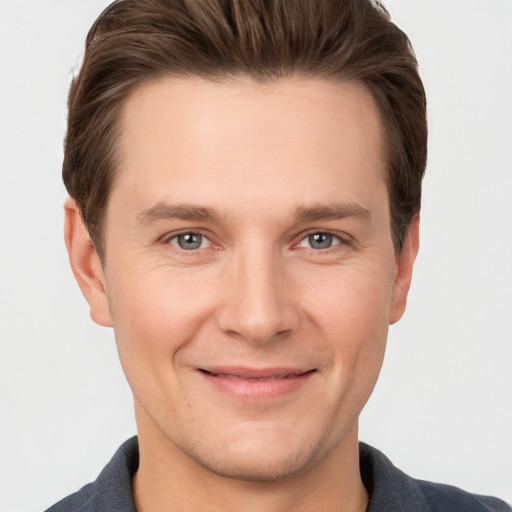 Joyful white young-adult male with short  brown hair and grey eyes