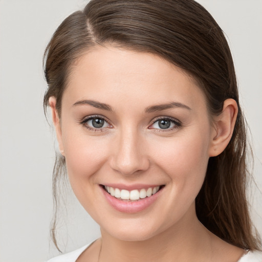 Joyful white young-adult female with medium  brown hair and grey eyes