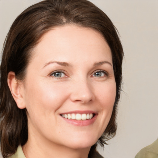 Joyful white young-adult female with medium  brown hair and grey eyes