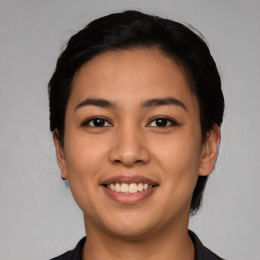 Joyful latino young-adult female with short  black hair and brown eyes