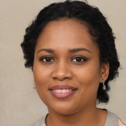 Joyful black young-adult female with long  brown hair and brown eyes