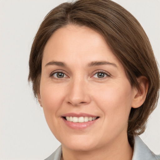 Joyful white young-adult female with medium  brown hair and grey eyes