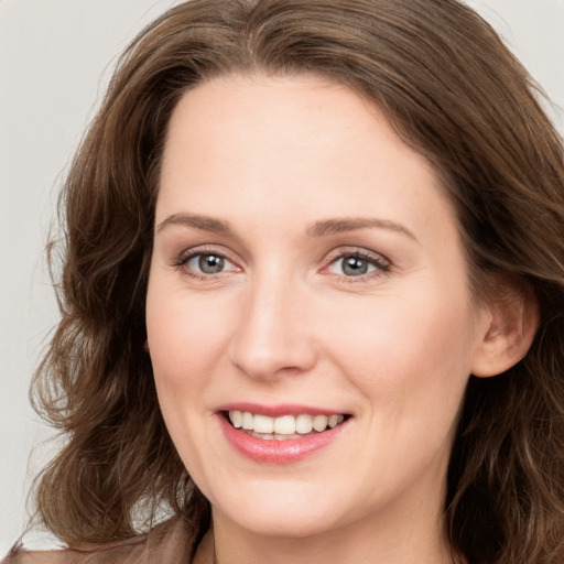 Joyful white young-adult female with long  brown hair and blue eyes