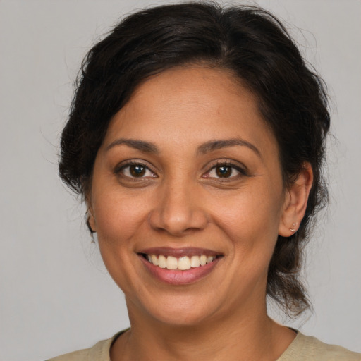 Joyful latino adult female with medium  brown hair and brown eyes