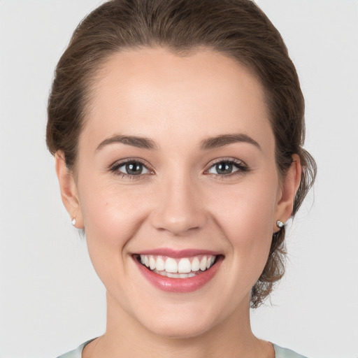 Joyful white young-adult female with medium  brown hair and grey eyes