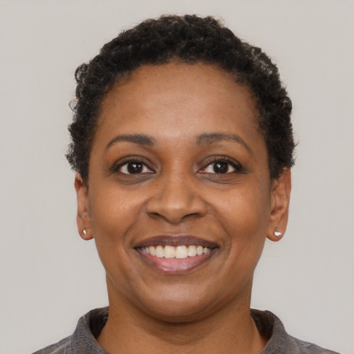 Joyful black young-adult female with short  black hair and brown eyes