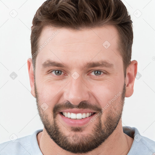 Joyful white young-adult male with short  brown hair and grey eyes