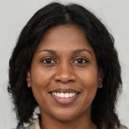 Joyful black adult female with long  brown hair and brown eyes