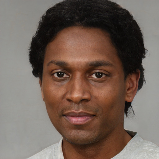 Joyful black adult male with short  black hair and brown eyes