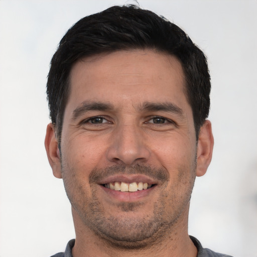 Joyful white young-adult male with short  black hair and brown eyes