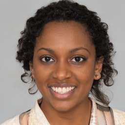 Joyful black young-adult female with long  brown hair and brown eyes