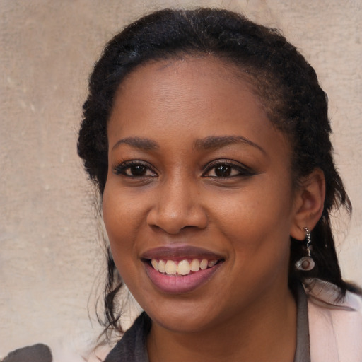 Joyful black young-adult female with long  brown hair and brown eyes