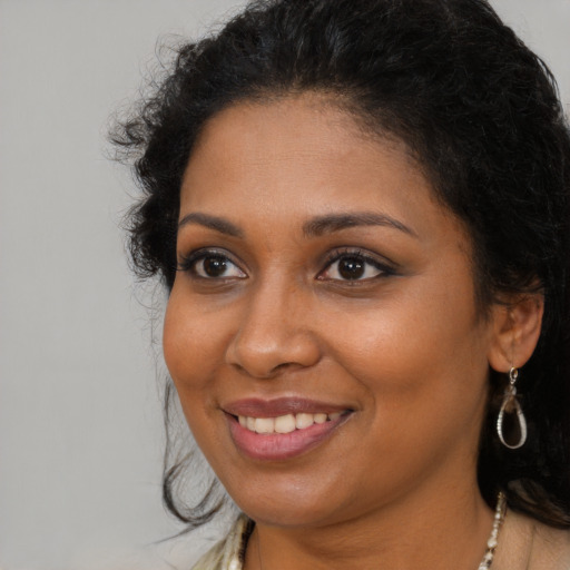 Joyful black young-adult female with long  brown hair and brown eyes